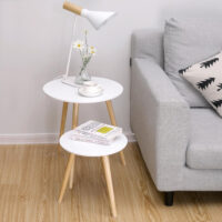 Modern eingerichtetes Wohnzimmer mit grauem Sofa und 2er-Set runder Beistelltische als stilvolle Ergänzung. Darauf eine Tischlampe, Tasse und Bücher.