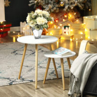Helles Wohnzimmer mit grünem Teppich, weißen Stühlen und dem 2er-Set runder Beistelltische als dekorative Ablage für Bücher, Tasse und Blumen.