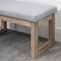 Eine graue Fussbank und Polsterhocker mit Holzbeinen.