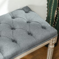 Graue Polsterbank im Vintage-Stil mit eleganter Knopfverzierung. Ein zeitloses Möbelstück für klassische Einrichtungen.