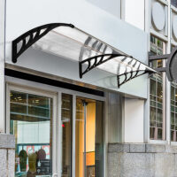 Transparentes Pultvordach für die Haustür, aus Polycarbonat und Aluminium, bietet modernen Wetterschutz.
