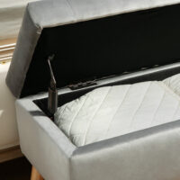 Graue Sitzbank mit stilvoller Samtoptik, integriertem Stauraum und Beinen aus massivem Gummiholz, perfekt für moderne Wohnräume.