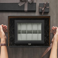 Elegante Uhrenbox aus schwarzem PU-Leder mit Glasdeckel und dunkelgrauen Nähten. Bietet Platz für 10 Uhren, schützt vor Staub und Kratzern und präsentiert die Sammlung stilvoll. Maße: 21 x 25 x 8,5 cm, Gewicht: 0,9 kg.